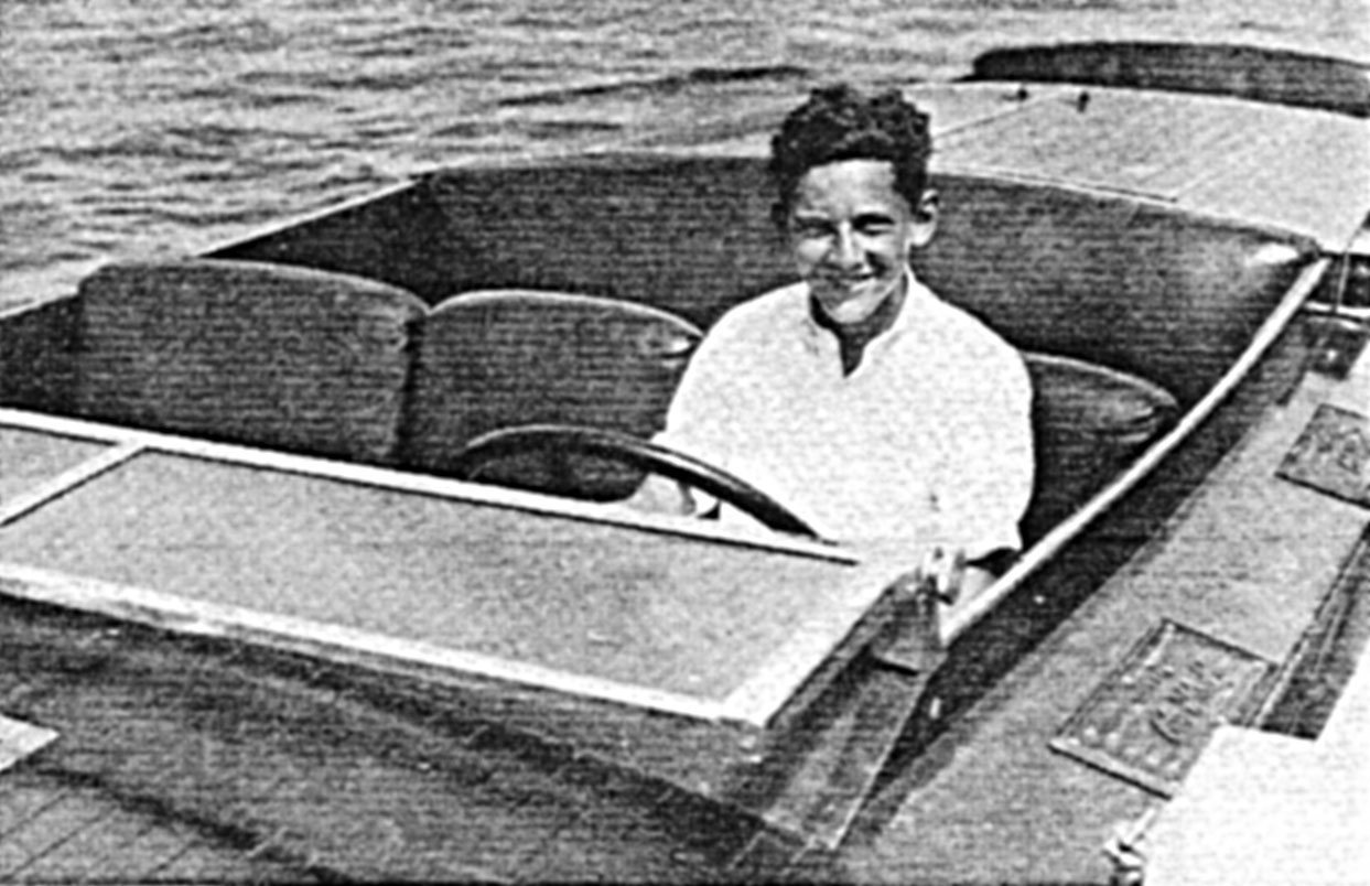 Roger Firestone, 16-year-old contestant, at the wheel of his Scripps-powered Baby Gar. Miss Elizabeth II. Having won three trophies in the runabout class, he can afford to smile.
